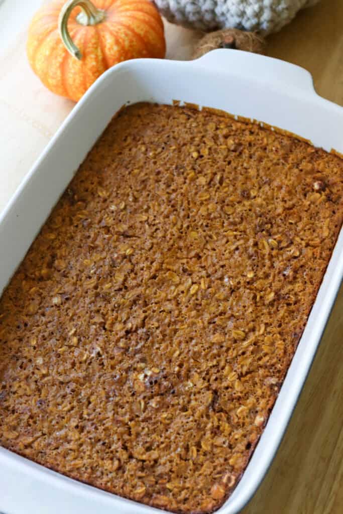 Healthy High Protein Baked Pumpkin Spice Oatmeal that has been baked with a pumpkin behind it