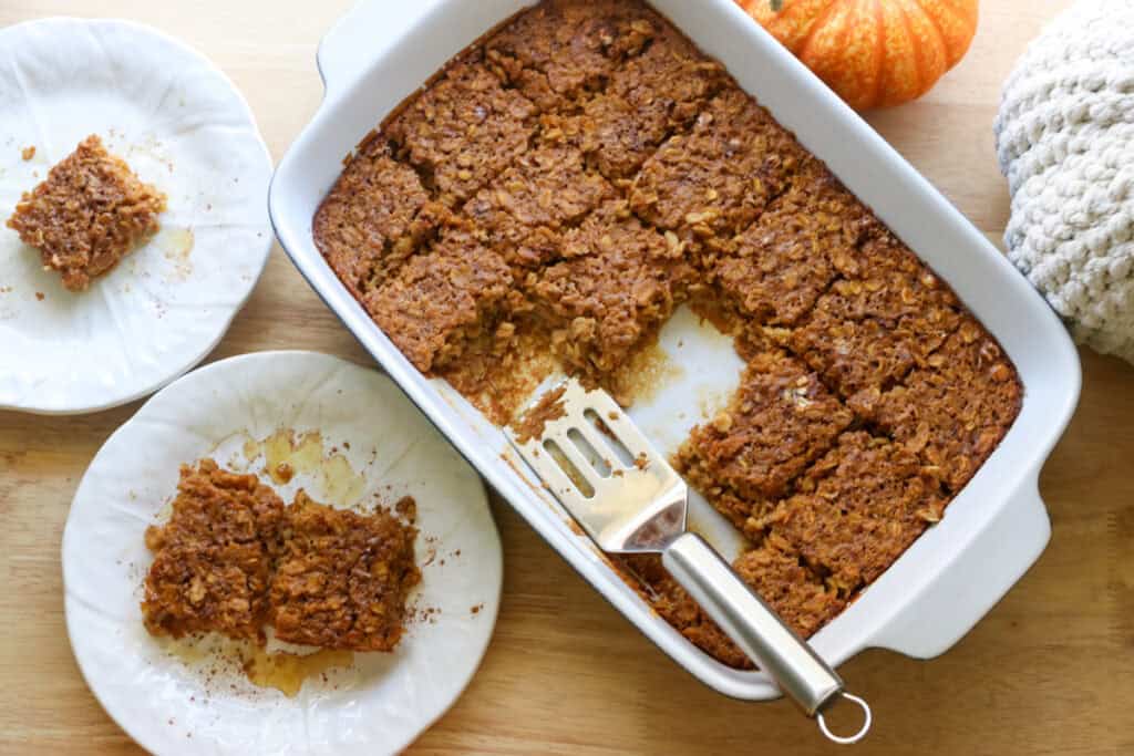 Healthy High Protein Baked Pumpkin Spice Oatmeal in a baking dish with two pieces on white plates