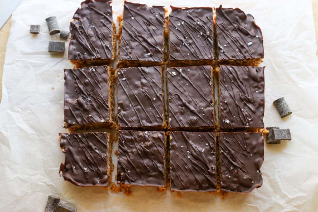Chocolate Peanut Butter Rice Krispie Bars that have been cut with chocolate chunks on white parchment