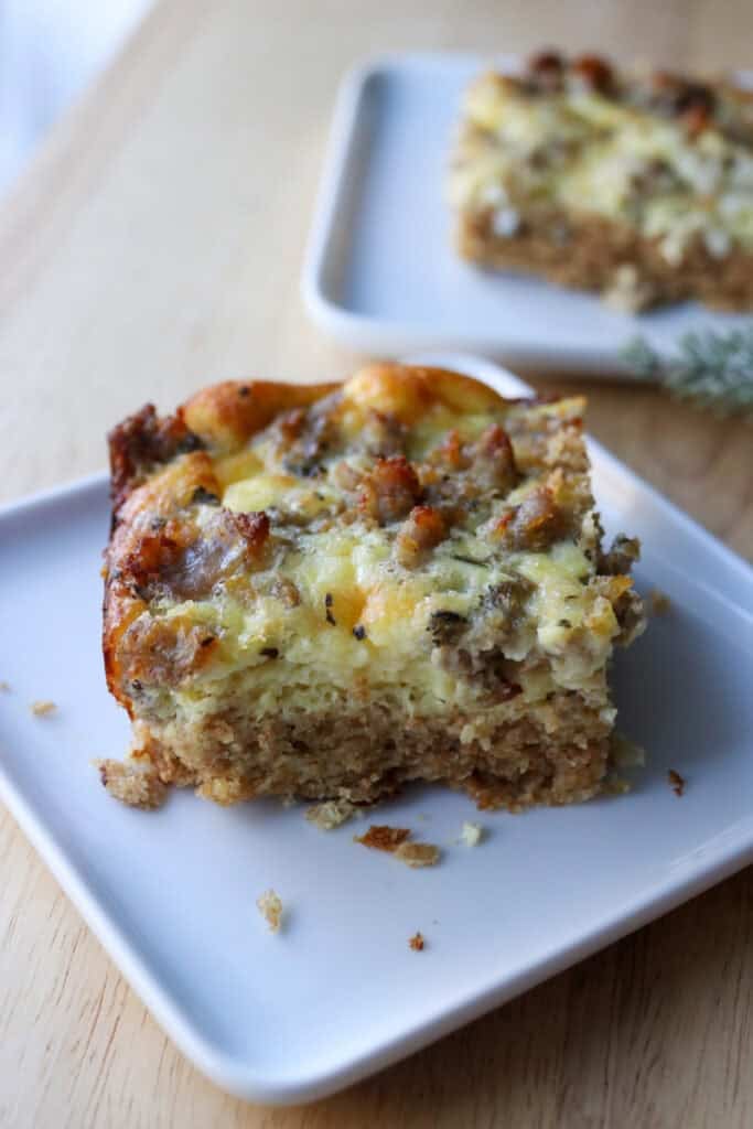 a slice of freshly milled breakfast casserole on a white plate with sausage on top