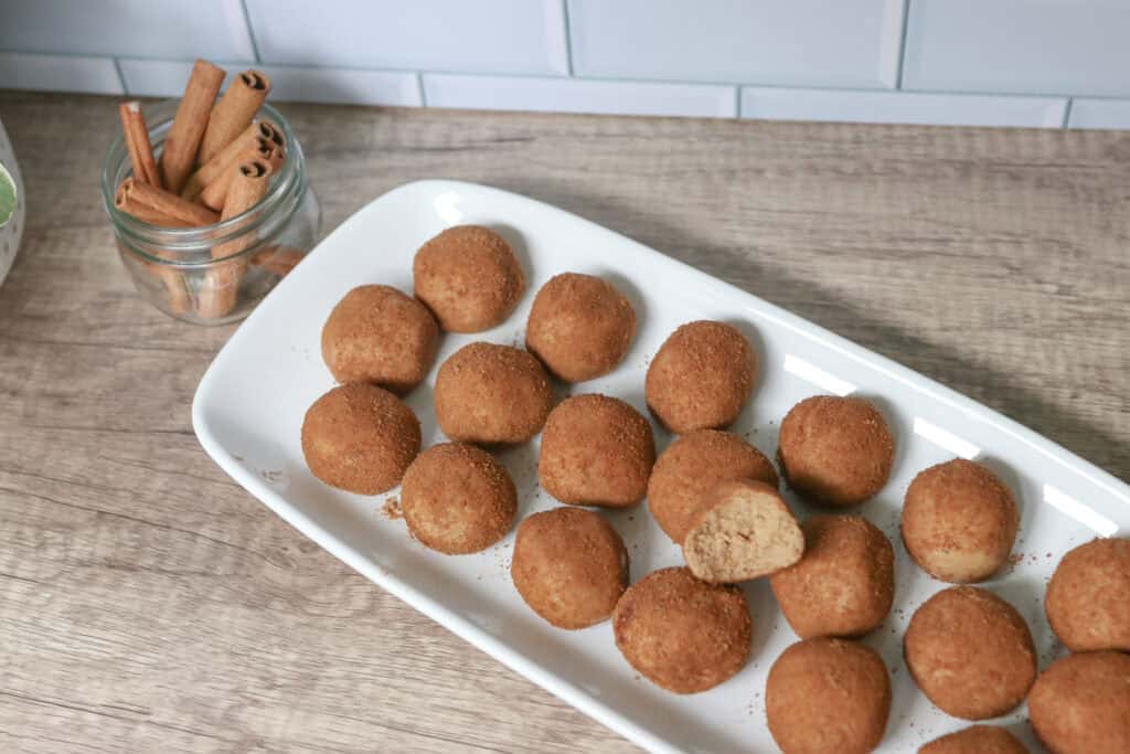 Healthy and Delicious Snickerdoodle Protein Balls on a tray with cinnamon sticks in a jar