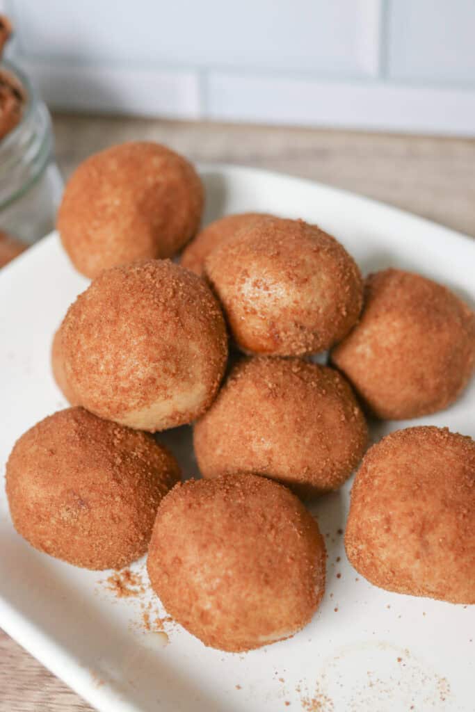 Healthy and Delicious Snickerdoodle Protein Balls covered in cinnamon and sugar and stacked on top of each other