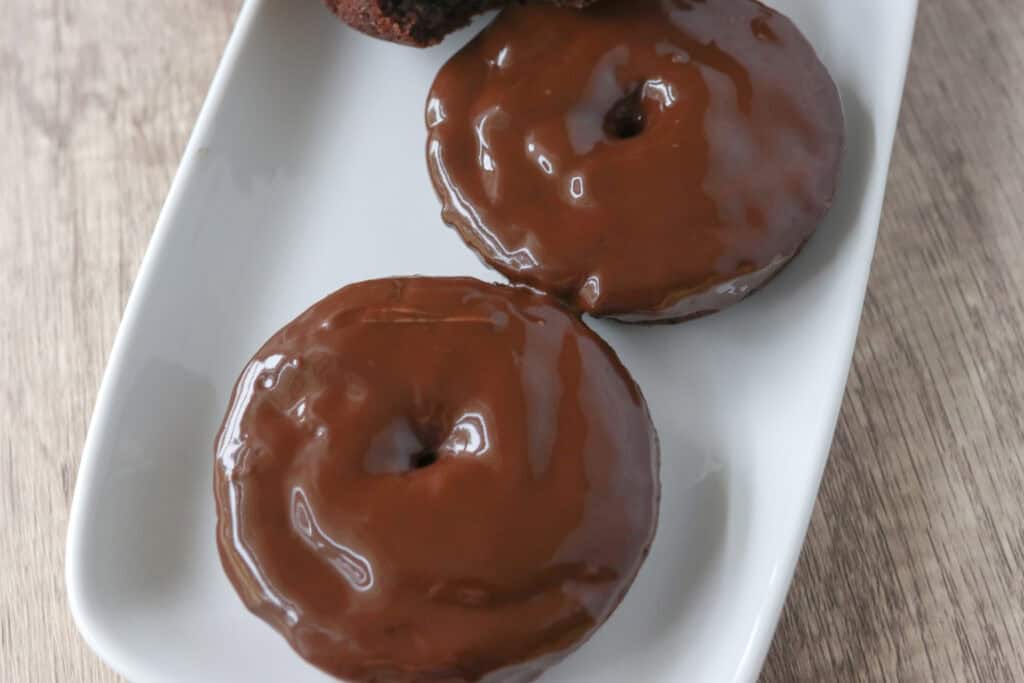two Healthy High Protein Chocolate Donuts with almond butter glaze on a white plate