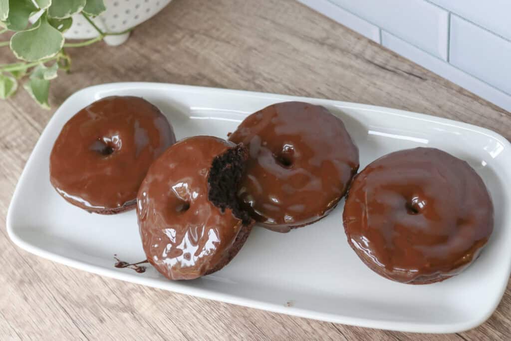 four Healthy High Protein Chocolate Donuts covered with Glaze on a white platter