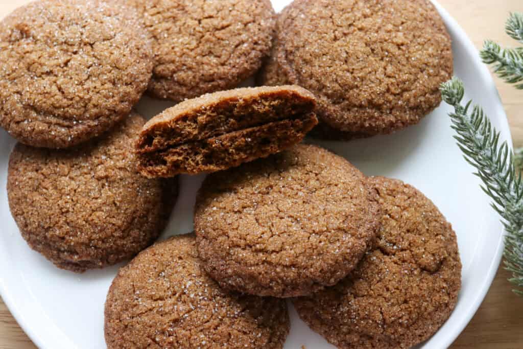 fresh milled gingersnap cookies on a white plate with one in half