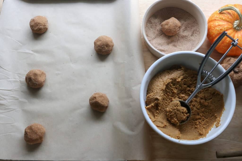 Freshly Milled Brown Butter Maple Pumpkin Cookies dough balls scooped onto a baking sheet covered in cinnamon and sugar