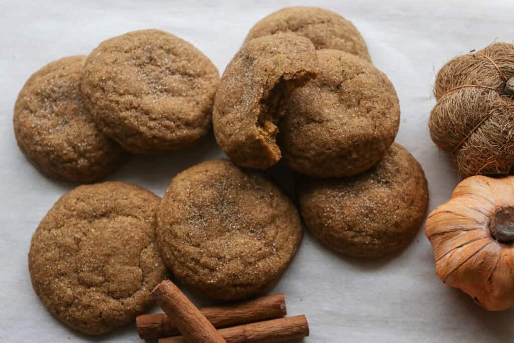 Freshly Milled Brown Butter Maple Pumpkin Cookies on white parchment paper with cinnamon sticks