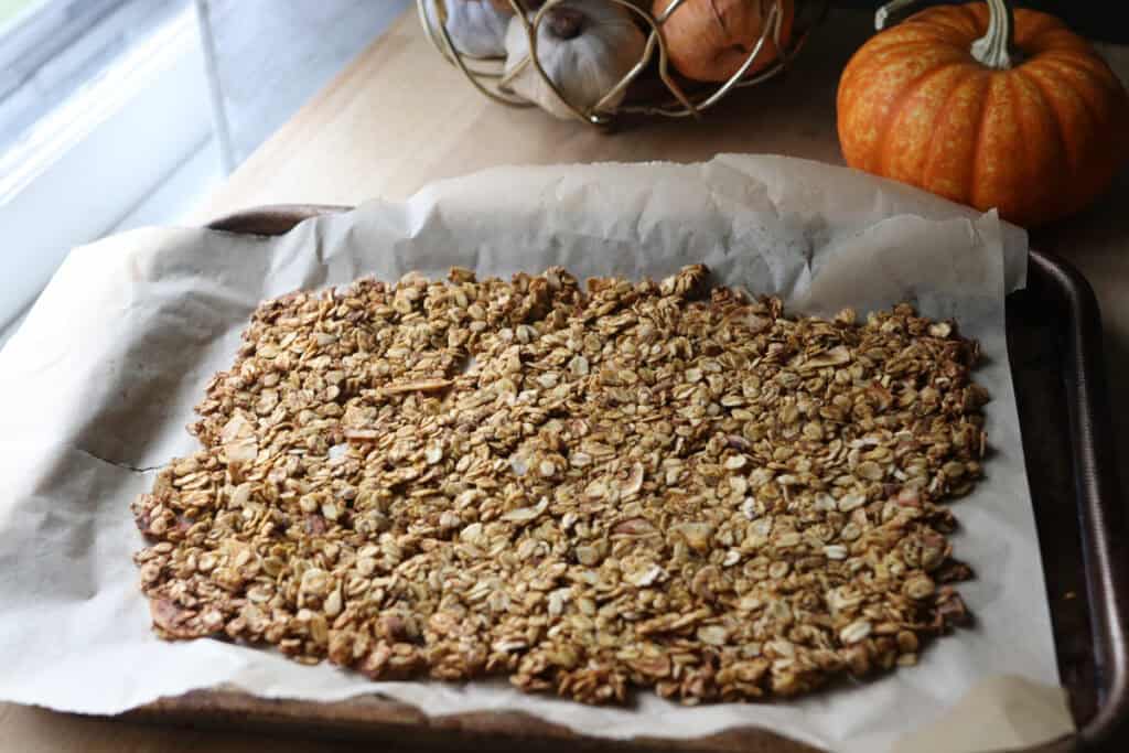 Crunchy Maple Pumpkin Spice Granola spread out on a baking sheet 
