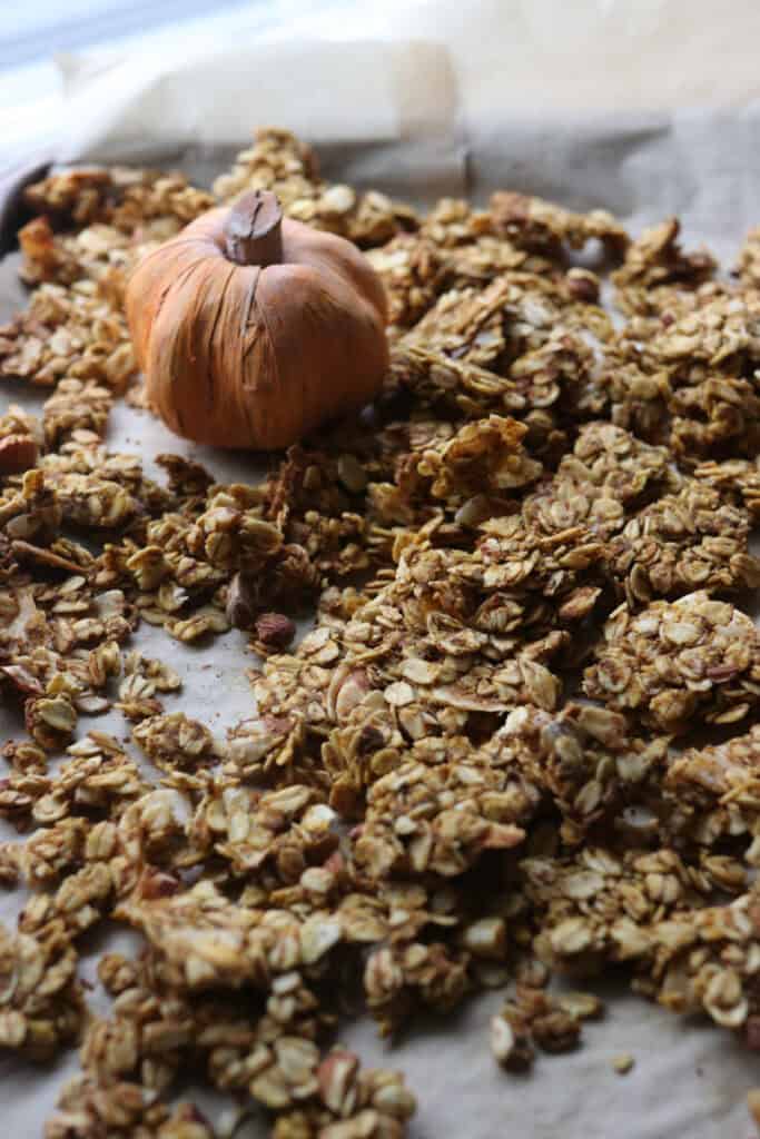 The Best Crunchy Maple Pumpkin Spice Granola on a baking sheet with a pumpkin