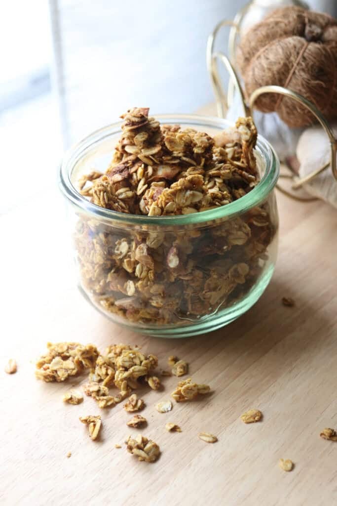 The Best Crunchy Maple Pumpkin Spice Granola in a glass jar on a wooden table