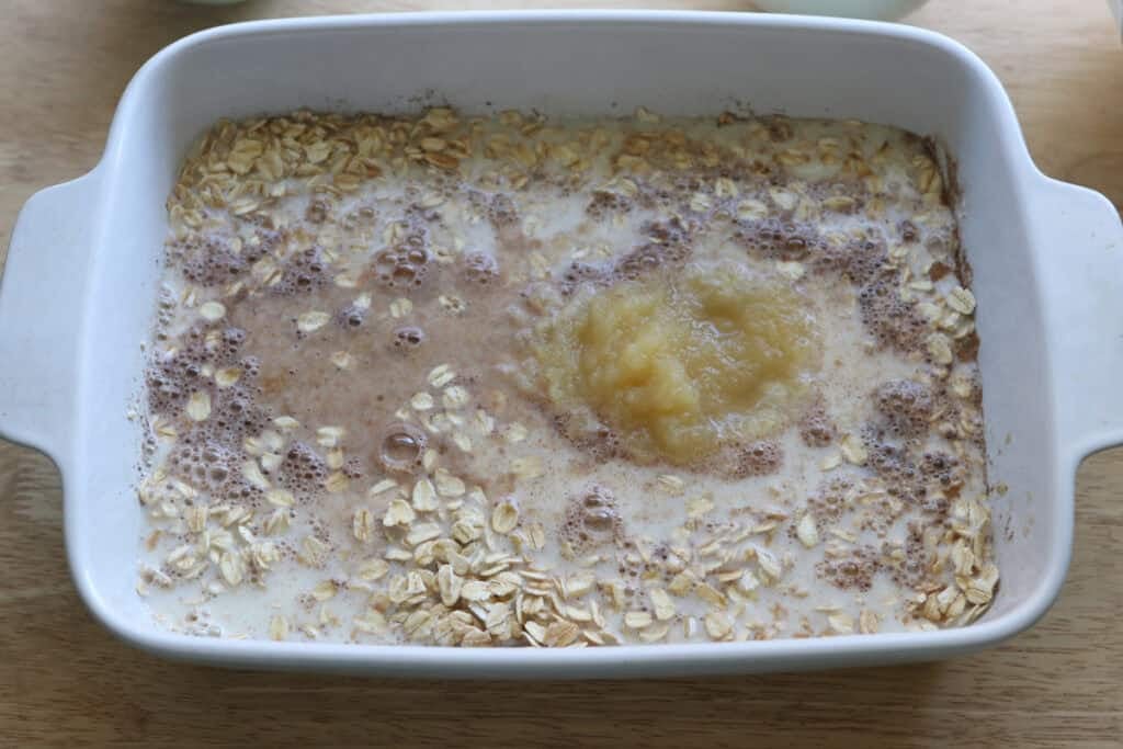 applesauce and milk added to a dish to make Healthy Cinnamon Coffee Cake Baked Oatmeal 