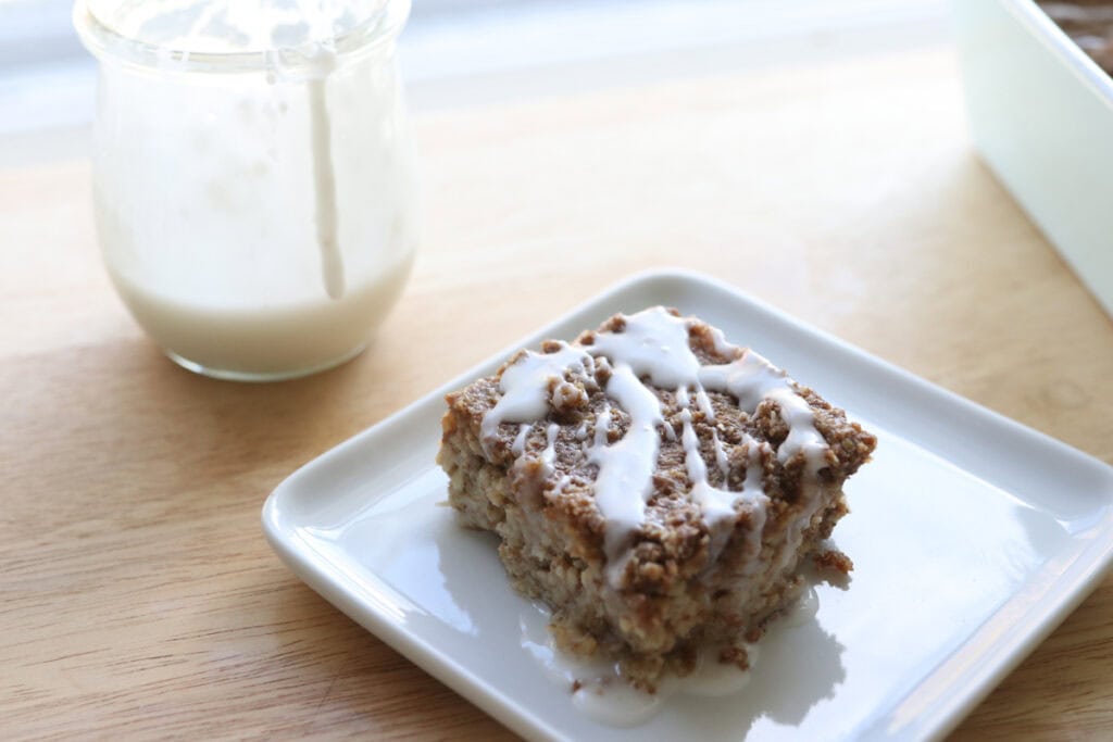 a slice of Healthy Cinnamon Coffee Cake Baked Oatmeal with a jar of icing beside it