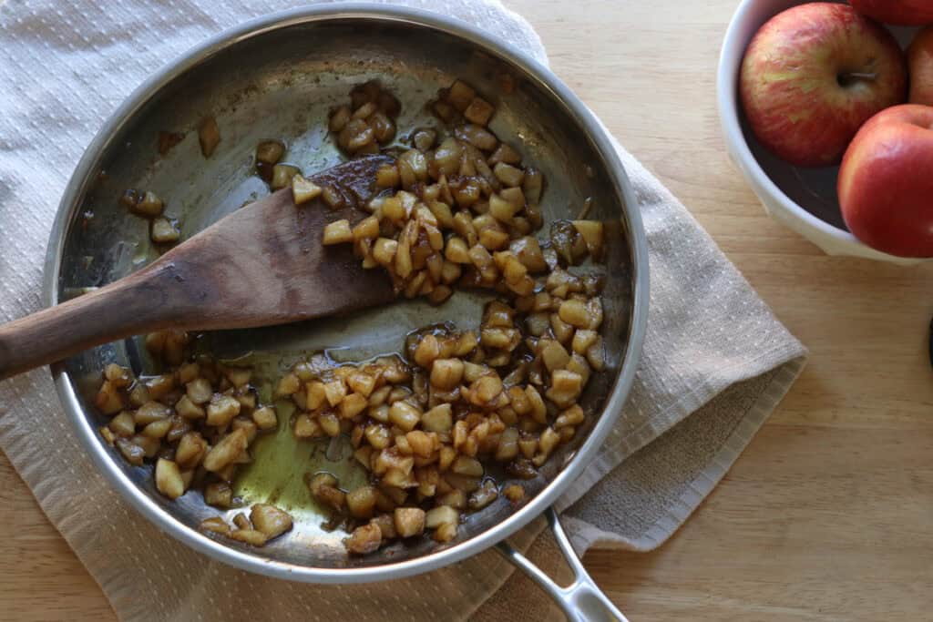 apples and maple syrup that have been cooked in a saucepan to put inside of freshly milled healthy apple hand pies