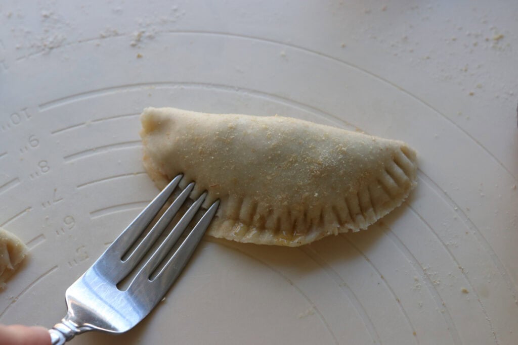 crimping the edges of a freshly milled healthy apple hand pie