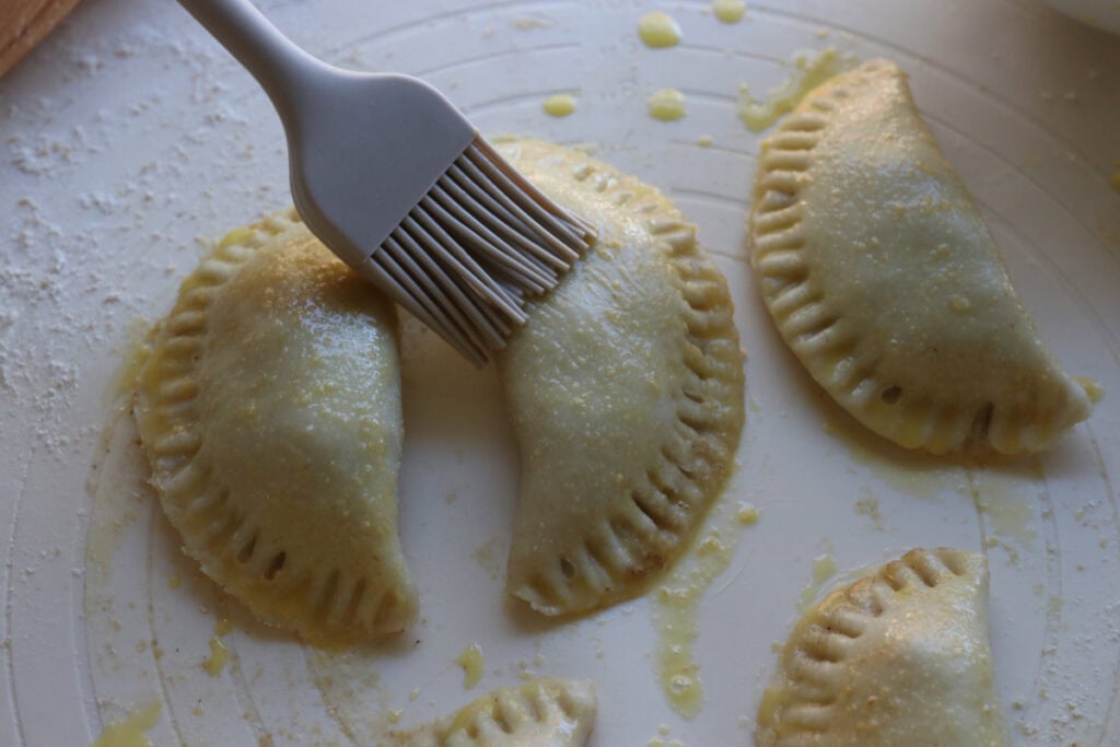 brushing freshly milled healthy apple hand pies with egg wash