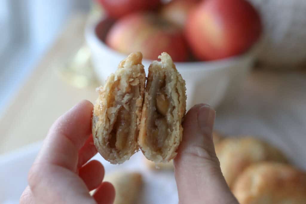 someone holding a fresh milled healthy apple hand pie cut in half