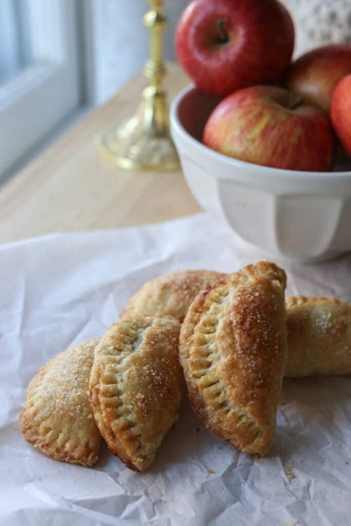 freshly milled healthy apple hand pies on a piece of parchment with sugar on top