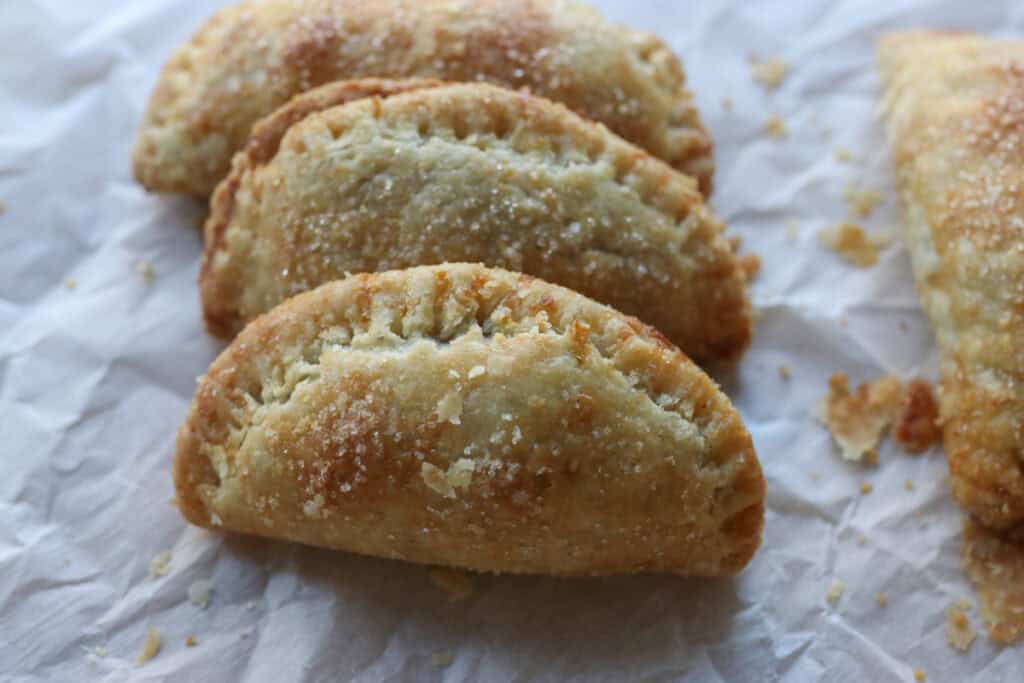 3 freshly milled healthy apple hand pies stacked together on a piece of white parchment paper