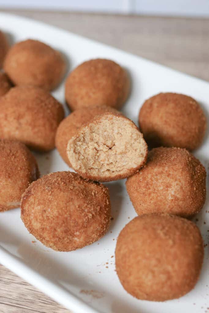 Healthy and Delicious Snickerdoodle Protein Balls with a bite taken out of one on a plate with 