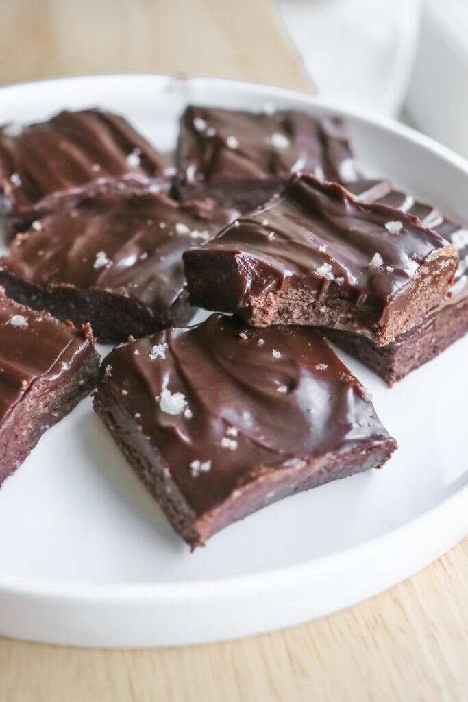 No Bake Protein Brownies with Chocolate Ganache on a white plate topped with flaky salt