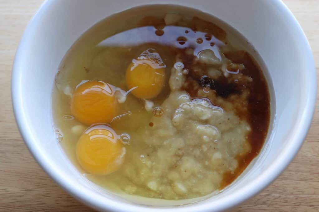eggs, mashed bananas, and vanilla in a white bowl to make The Best High Protein Easy Banana Muffins