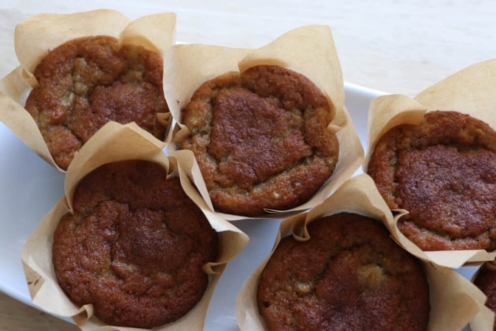 The Best High Protein Easy Banana Muffins in muffin liners on a white platter