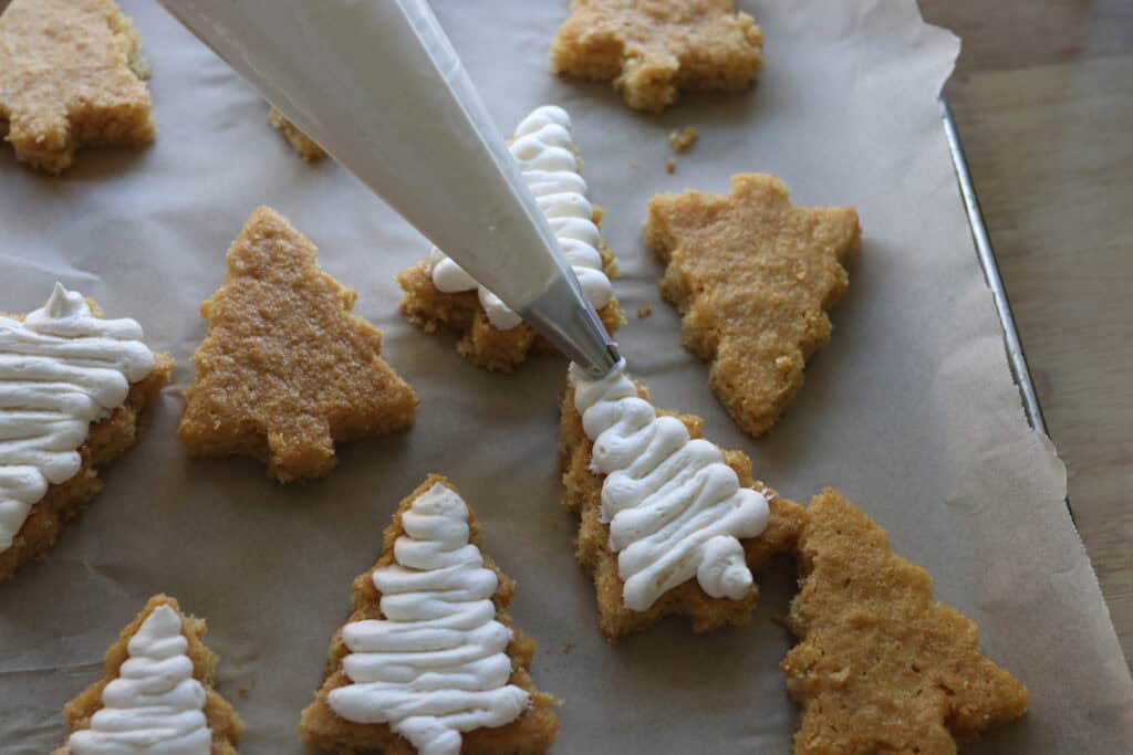 icing Fresh Milled Little Debbie Christmas Tree Cakes on a piece of parchment paper