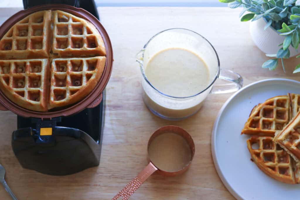 Freshly Milled Healthy High Protein Waffles on a plate with waffle batter and a waffle maker