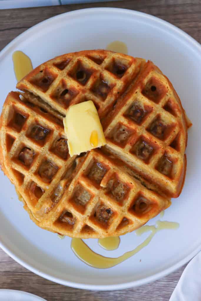 Freshly Milled Healthy High Protein Waffle on a white plate topped with maple syrup and butter