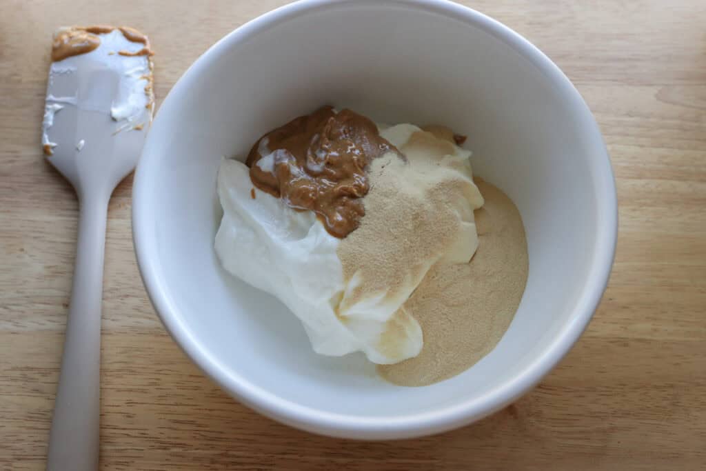 protein powder, yogurt, and peanut butter in a bowl to make High Protein Chocolate Peanut Butter Yogurt Cups