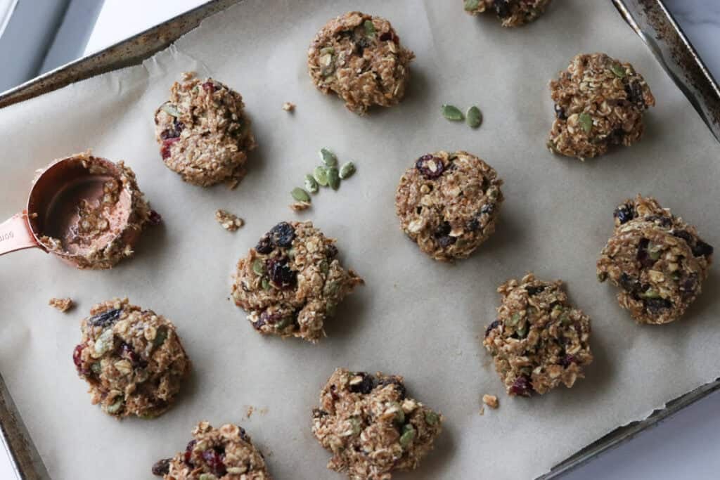 Easy and Healthy Breakfast Oatmeal Cookies scooped onto a cookie sheet with parchment paper and a measuring cup