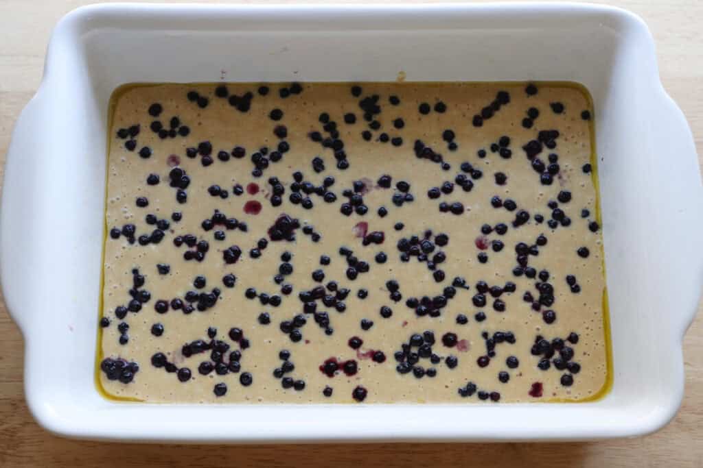 fresh milled sheet pan protein pancake batter in a white casserole dish with blueberries on top