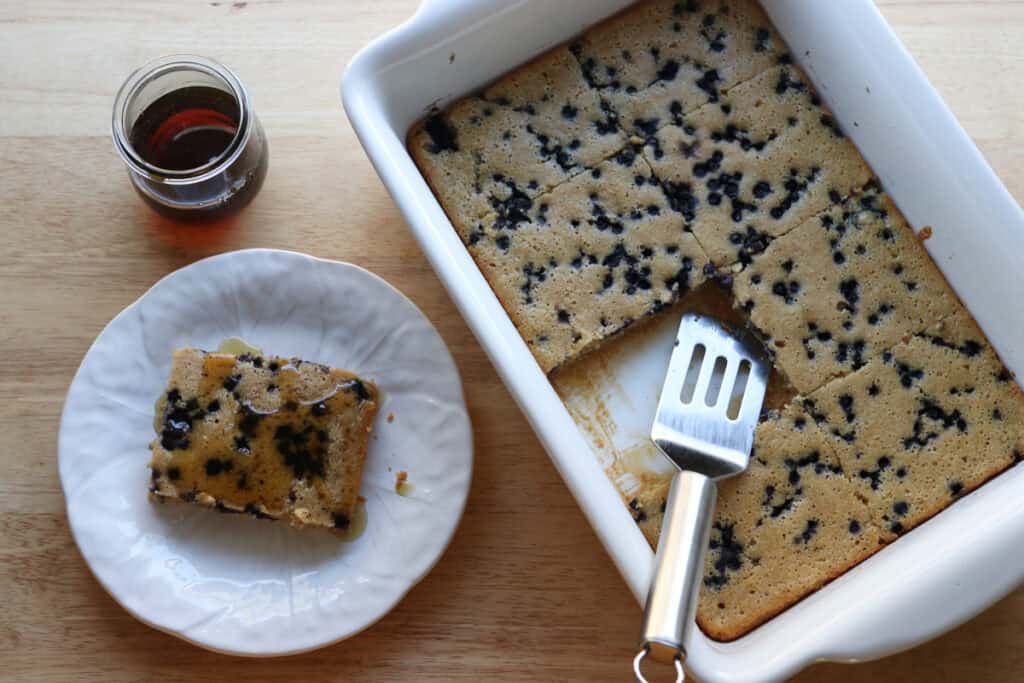 fresh milled sheet pan protein pancakes with a spatula and slice on a white plate
