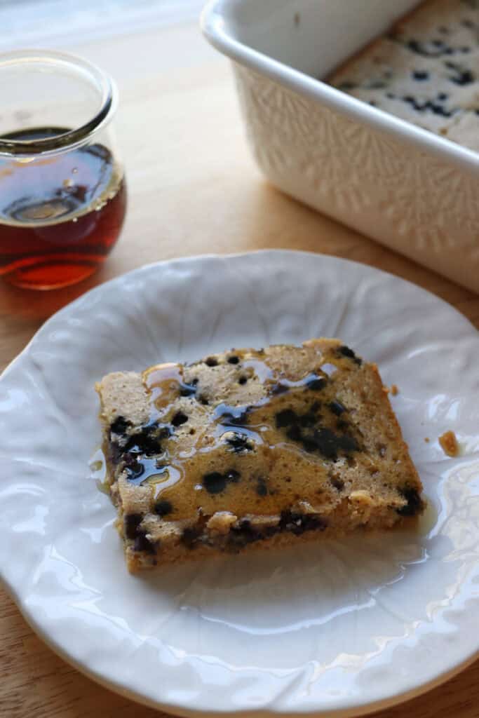 a slice of fresh milled sheet pan protein pancake on a plate with maple syrup on top