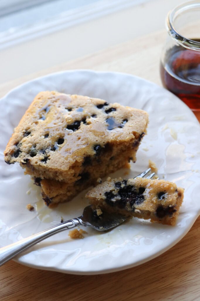 two slices of fresh milled sheet pan protein pancakes stacked together covered in maple syrup