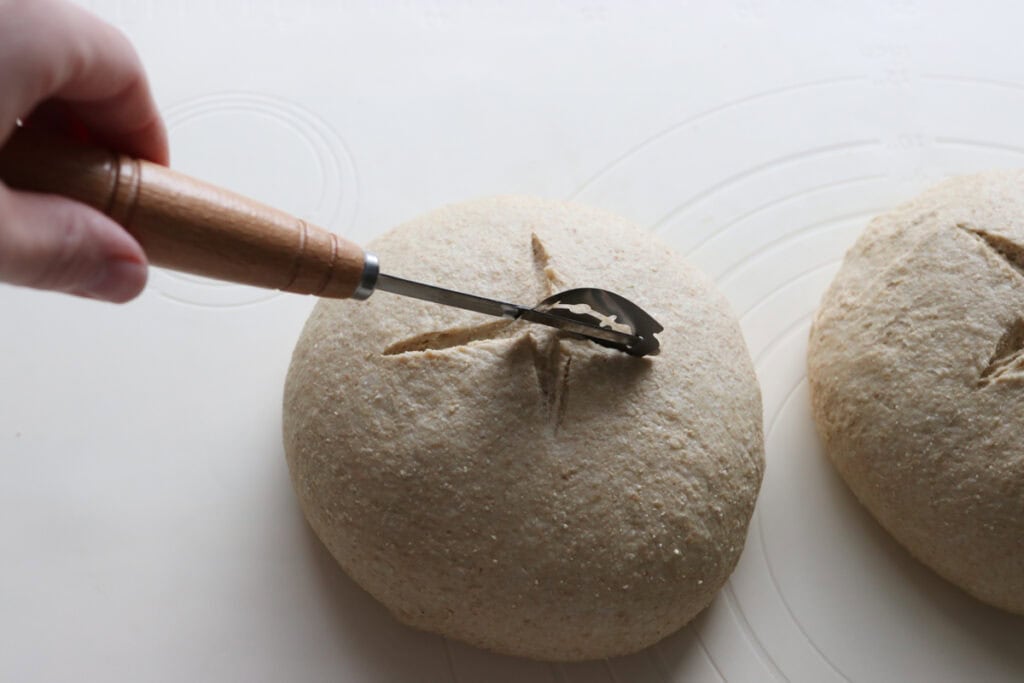 scoring the top of a freshly milled soup bread bowl