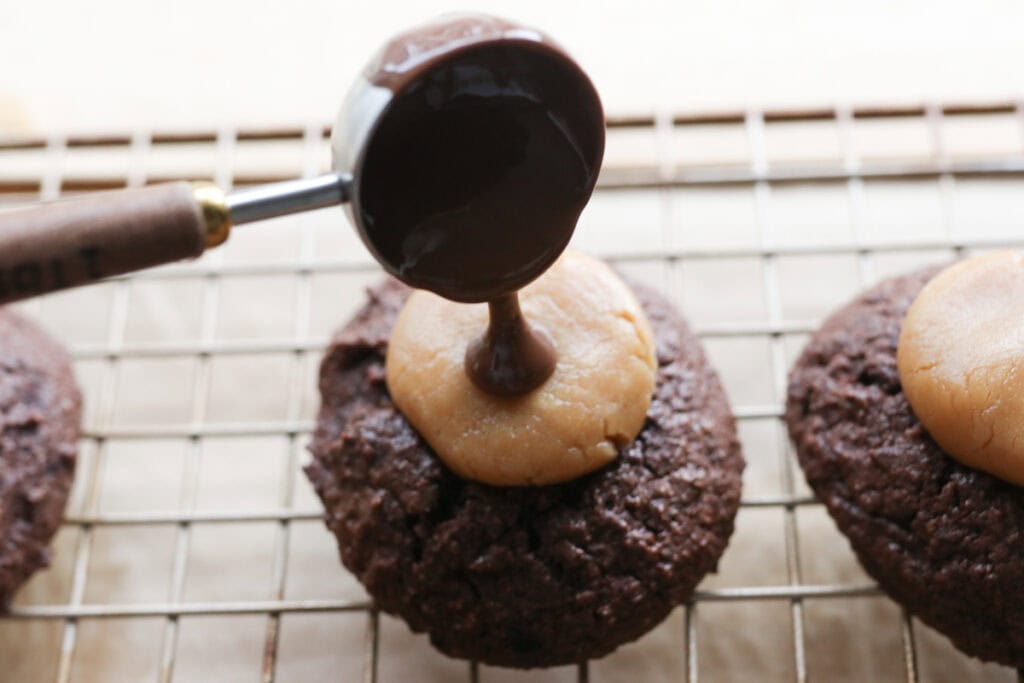 pouring melted chocolate over the fresh milled buckeye brownie cookies with a tablespoon
