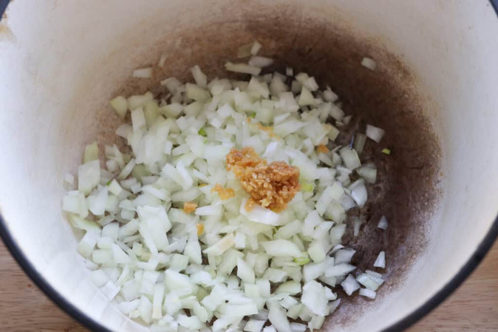 onion and garlic in a pan to make creamy chicken enchilada soup