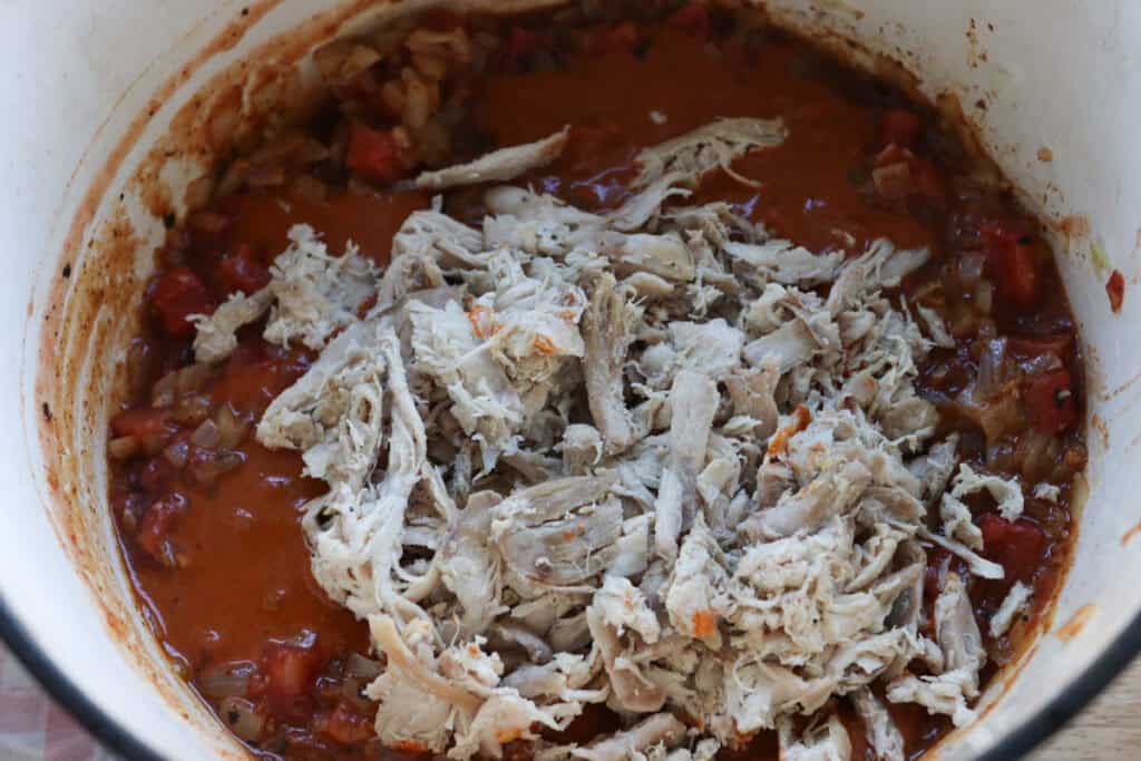 tomatoes and chicken add to a pot to make creamy chicken enchilada soup