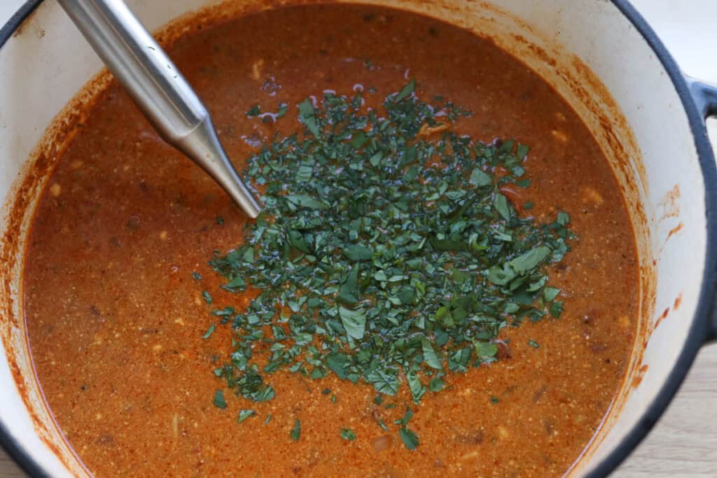 cilantro and sour cream added to a pot to make creamy chicken enchilada soup