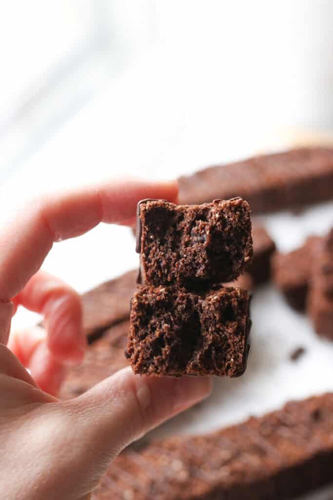 someone holding a slice of fresh milled double chocolate biscotti that has been broken in half