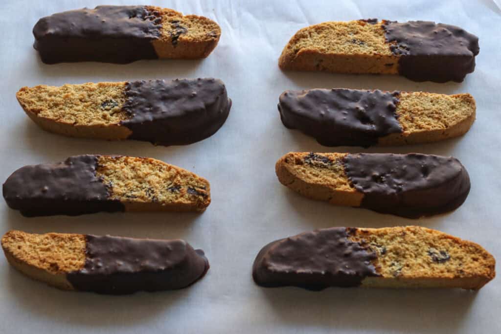 pieces of freshly milled chocolate chip biscotti that have been dipped in chocolate on white parchment