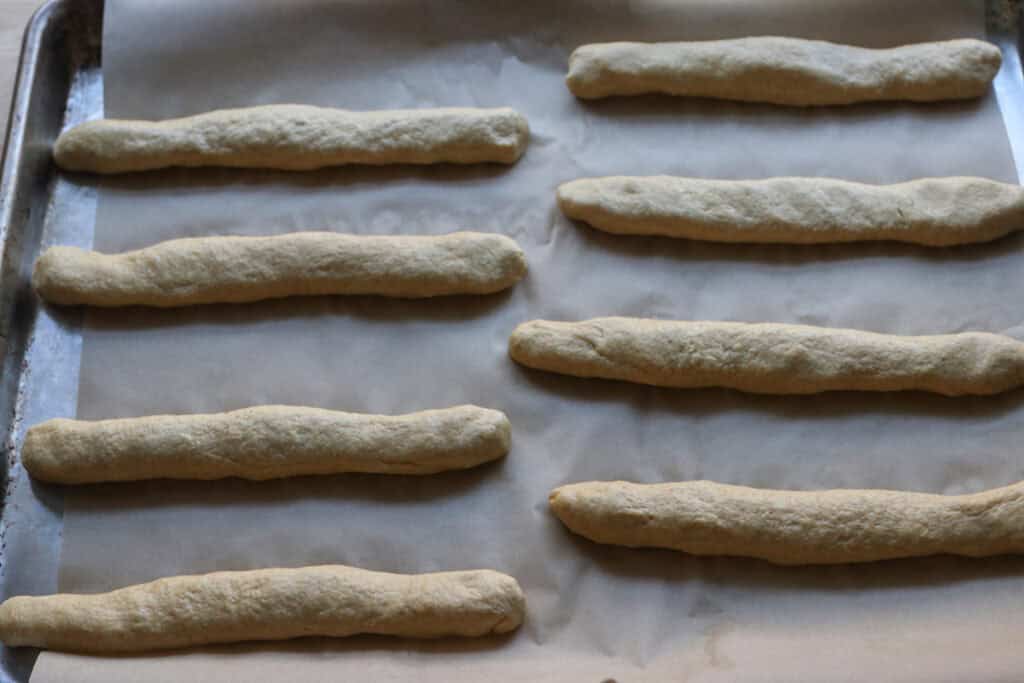 fresh milled sourdough breadsticks rising on a baking sheet with parchment paper