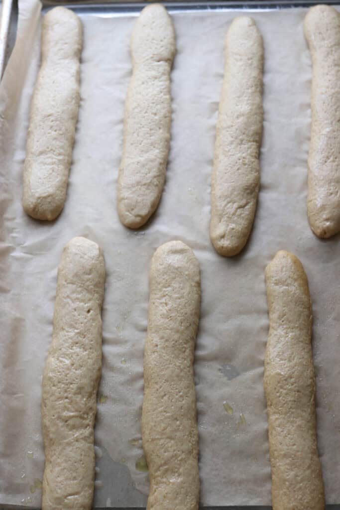 fresh milled sourdough breadsticks on a piece of parchment paper that have risen