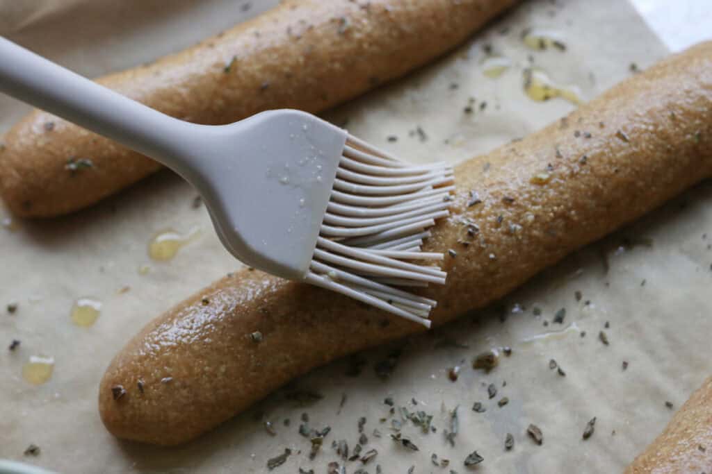 brushing garlic butter onto a fresh milled sourdough breadstick