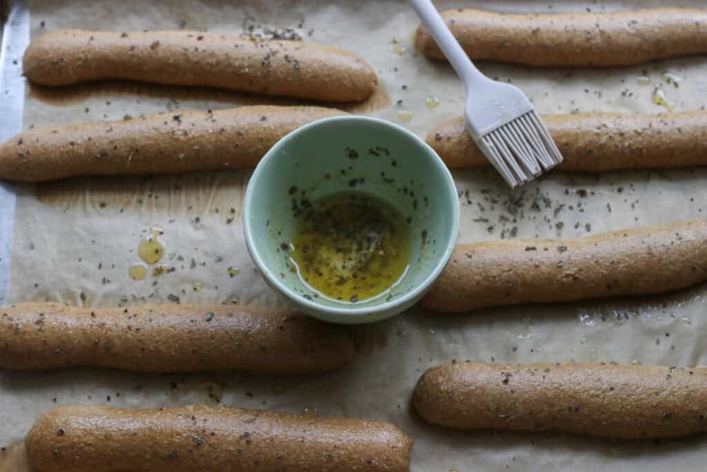fresh milled sourdough breadsticks on a pan with garlic butter in a bowl