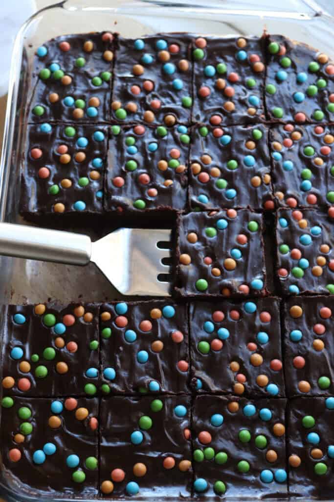 freshly milled fudgy cosmic brownies in a glass pan with a spatula