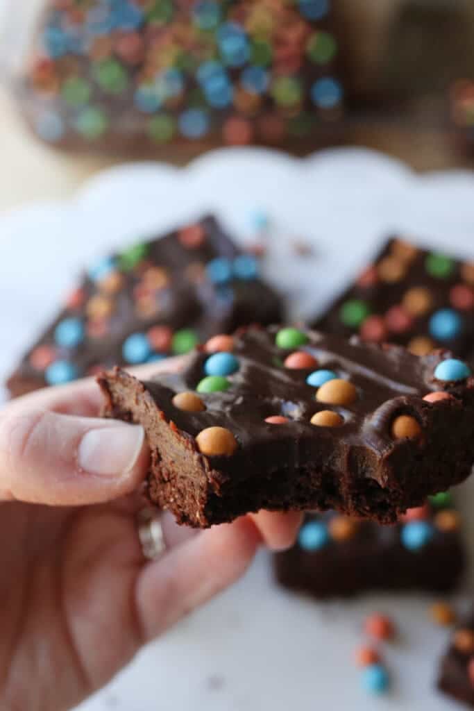 someone holding a freshly milled fudgy cosmic brownie with a bite taken out of it