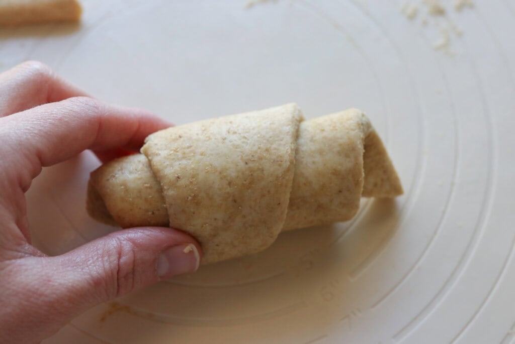 rolling up dough to form a fresh milled flaky buttery croissant