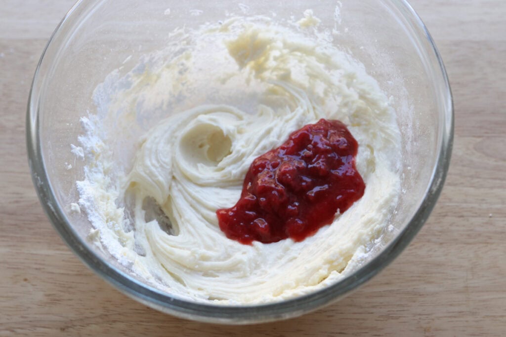 cream cheese and strawberry filling in a bowl to make the glaze for Freshly Milled Valentine's Strawberry Cinnamon Rolls